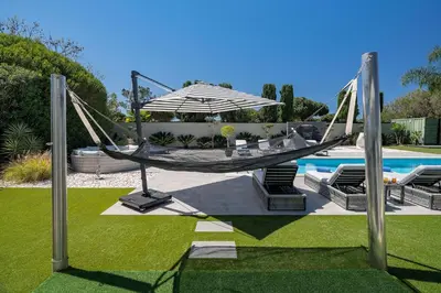 a hammock and an umbrella next to a pool at Villa Allegra - Quinta do Lago in Almancil