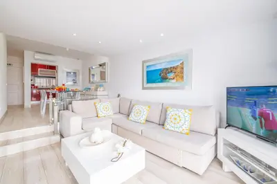 a living room with a white couch and a flat screen tv at Luxurious Seaview Apartment with pool 5min Beach in Albufeira