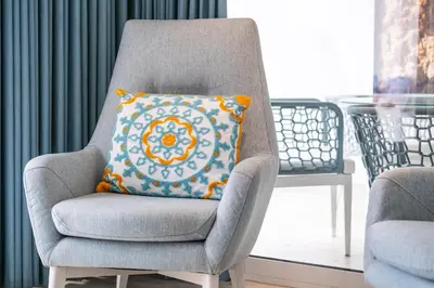 a gray chair with an orange pillow in a room at Luxurious Seaview Apartment with pool 5min Beach in Albufeira