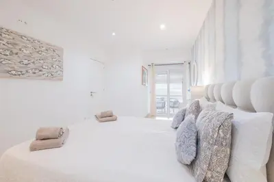 a white bedroom with a large white bed with pillows at Luxurious Seaview Apartment with pool 5min Beach in Albufeira