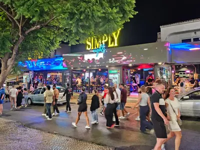 a group of people walking down a street at night at Guest House Casa Ramos on the Strip in Albufeira