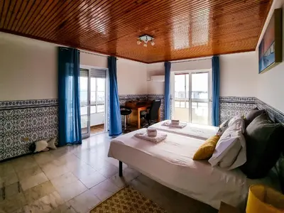 a bedroom with a large bed with blue curtains at FLH Faro Family Flat with Balcony in Faro