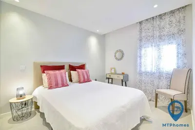a white bedroom with a large bed and a chair at Vale Mangude A by MTPhomes in Albufeira