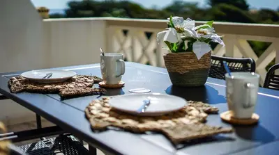 a blue table with plates and a vase of flowers at Aveiros Beach Apartment Ocean View - By Dalma Portuguesa in Albufeira