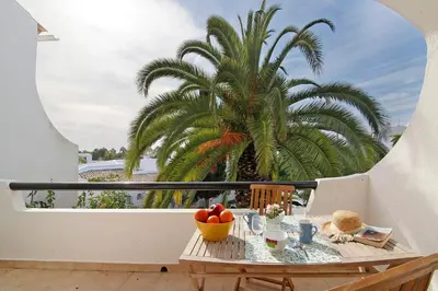 a table with fruit on a balcony with a palm tree at Apartamento São Rafael in Albufeira