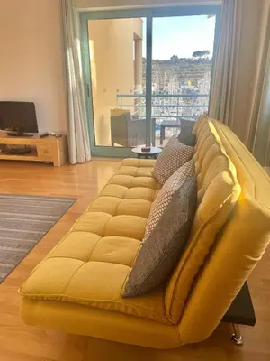 a yellow couch in a living room with a large window at Marina View Apartment in Albufeira