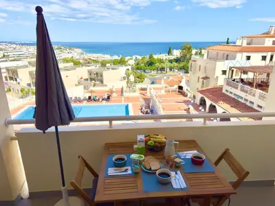 a balcony with a table and an umbrella and a pool at Apartment Les 3 Dauphins in Albufeira in Albufeira