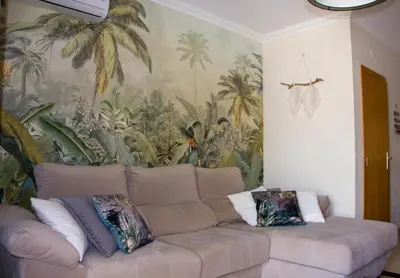a couch in a living room with a mural of palm trees at Sul House in Albufeira
