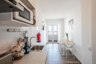 a kitchen with a sink and a table with chairs at BeGuest Oceanic Rainbow Apt in Albufeira