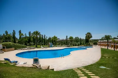 a large swimming pool in a resort with chairs and trees at Villa facing the pool by Algarve Dream Holidays in Fontainhas
