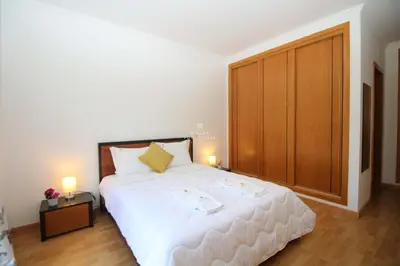 a bedroom with a large white bed and a wooden closet at Apartment Garcas Lounge - By Dalma Portuguesa in Albufeira