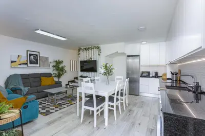 a kitchen and living room with a white table and chairs at Vilar do Jardim - Terrace and Pool - Vilamoura in Quarteira
