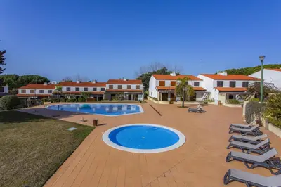 a resort with a swimming pool and chairs and buildings at Vilar do Jardim - Terrace and Pool - Vilamoura in Quarteira