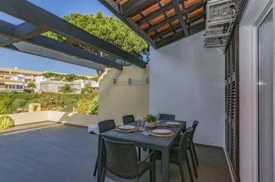 a dining room with a table and chairs on a patio at Vilar do Jardim - Terrace and Pool - Vilamoura in Quarteira