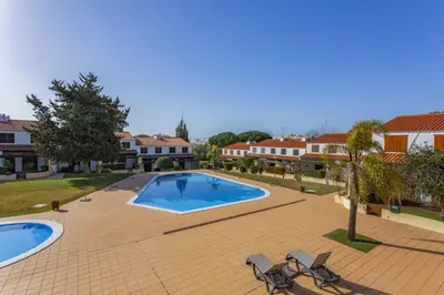 a swimming pool with two chairs and a house at Vilar do Jardim - Terrace and Pool - Vilamoura in Quarteira