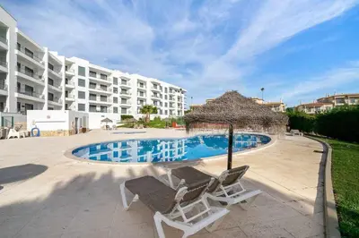two chairs and a swimming pool in front of a building at Vista das Ondas 02B - Dream Lodging in Albufeira
