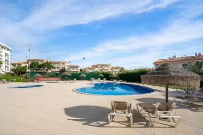 a swimming pool with two chairs and an umbrella at Vista das Ondas 02B - Dream Lodging in Albufeira