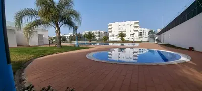 a courtyard with a pool and palm trees and buildings at Albufeira Apartment Pool & Tennis in Albufeira