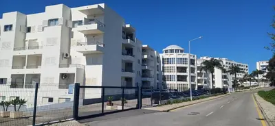 a white building with a fence next to a street at Albufeira Apartment Pool & Tennis in Albufeira