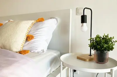 a bed with a pillow and a table with a lamp at Albufeira Central Apartment, 10 mins walk to beach in Albufeira