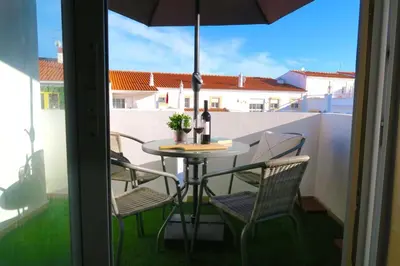 a table and chairs on a balcony with an umbrella at Albufeira Central Apartment, 10 mins walk to beach in Albufeira