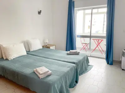 a bedroom with a bed with blue sheets and a window at Sunny House Albufeira in Albufeira