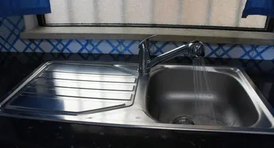 a kitchen sink with water pouring from a faucet at CASA ROMAN Poente da Aldeia in Albufeira