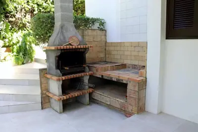 an outdoor pizza oven sitting on a patio at Villa Hibiscus, great location in Vilamoura, lush green lawns and garden in Quarteira