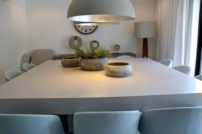 a dining room table with chairs and a light fixture at Villa Hibiscus, great location in Vilamoura, lush green lawns and garden in Quarteira