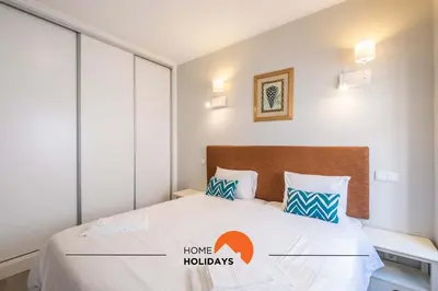 a bedroom with a bed with white sheets and blue pillows at #096 Casa Antonieta 1 by Home Holidays in Albufeira