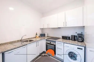 a kitchen with white cabinets and a washer and dryer at #096 Casa Antonieta 1 by Home Holidays in Albufeira
