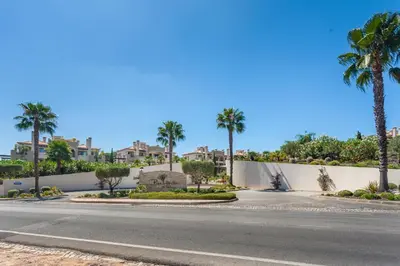 a street with palm trees and a white wall at Vilamoura Pine Hills Villa in Vilamoura