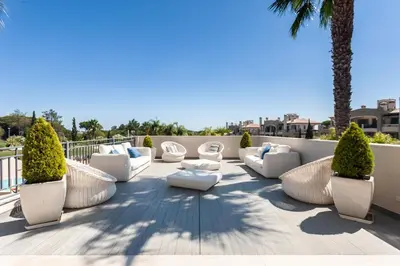 a patio with white furniture and palm trees at Vilamoura Pine Hills Villa in Vilamoura