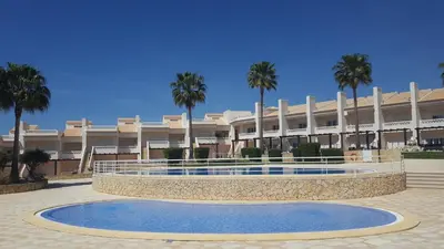 a large building with palm trees in front of it at Casa Felicidade in Albufeira