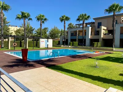 a swimming pool in front of a house with palm trees at Janelas do Oceano - Casa de Ferias T3 Vilamoura in Vilamoura