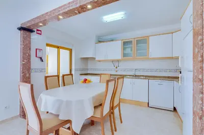 a kitchen and dining room with a table and chairs at AL - Apartamento Atlântida Mar in Quarteira