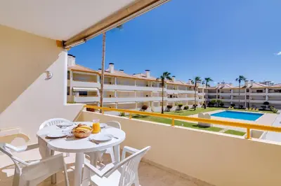 a balcony with a table and chairs and a pool at AL - Apartamento Atlântida Mar in Quarteira