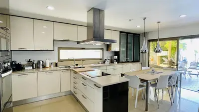 a kitchen with white cabinets and a table with chairs at Praia by Check-in Portugal in Albufeira