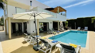 a pool with chairs and an umbrella next to a house at Praia by Check-in Portugal in Albufeira