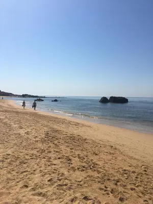 a beach with people walking on the sand and the water at Apartamento Sea Shell in Albufeira