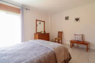 a bedroom with a bed and a mirror and a chair at Apartamento Sea Shell in Albufeira