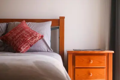 a bed with a red pillow and a wooden night stand at Apartamento Sea Shell in Albufeira