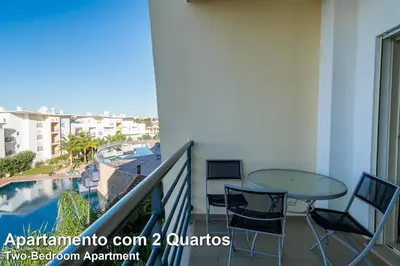 a balcony with a table and chairs and a swimming pool at Akisol Albufeira Rainbow in Albufeira