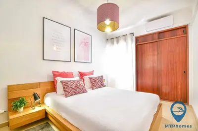 a bedroom with a bed with white sheets and pink pillows at Onda Azul by MTPhomes in Albufeira