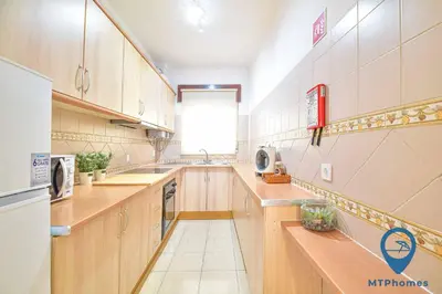 a large kitchen with wooden cabinets and a window at Onda Azul by MTPhomes in Albufeira