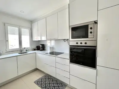 a white kitchen with white cabinets and a microwave at Nutmeg - 50mtrs to beach - by HD PROPERTIES in Quarteira