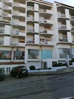 a large white building with cars parked in front of it at Apartamento Maria do Céu Villa Magna in Albufeira