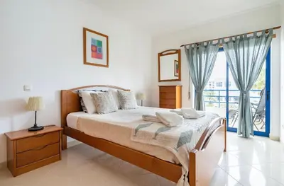 a bedroom with a bed and a balcony at Quarteira beach house in Quarteira