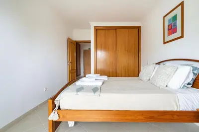 a bedroom with a large bed with a wooden headboard at Quarteira beach house in Quarteira