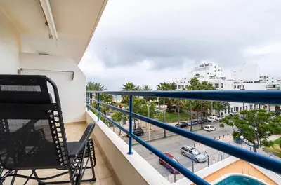 a balcony with a chair and a view of a street at Quarteira beach house in Quarteira